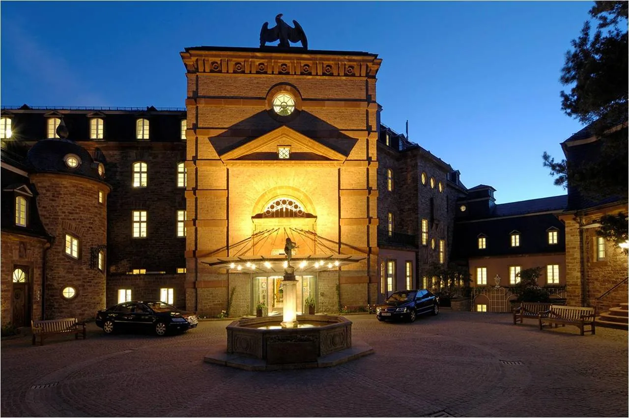 Beleuchtetes Portal mit Brunnen im Innenhof von Schloss Bühlerhöhe am Abend